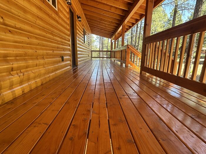 Log cabin wraparound porch after stain, natural wood grain preserved